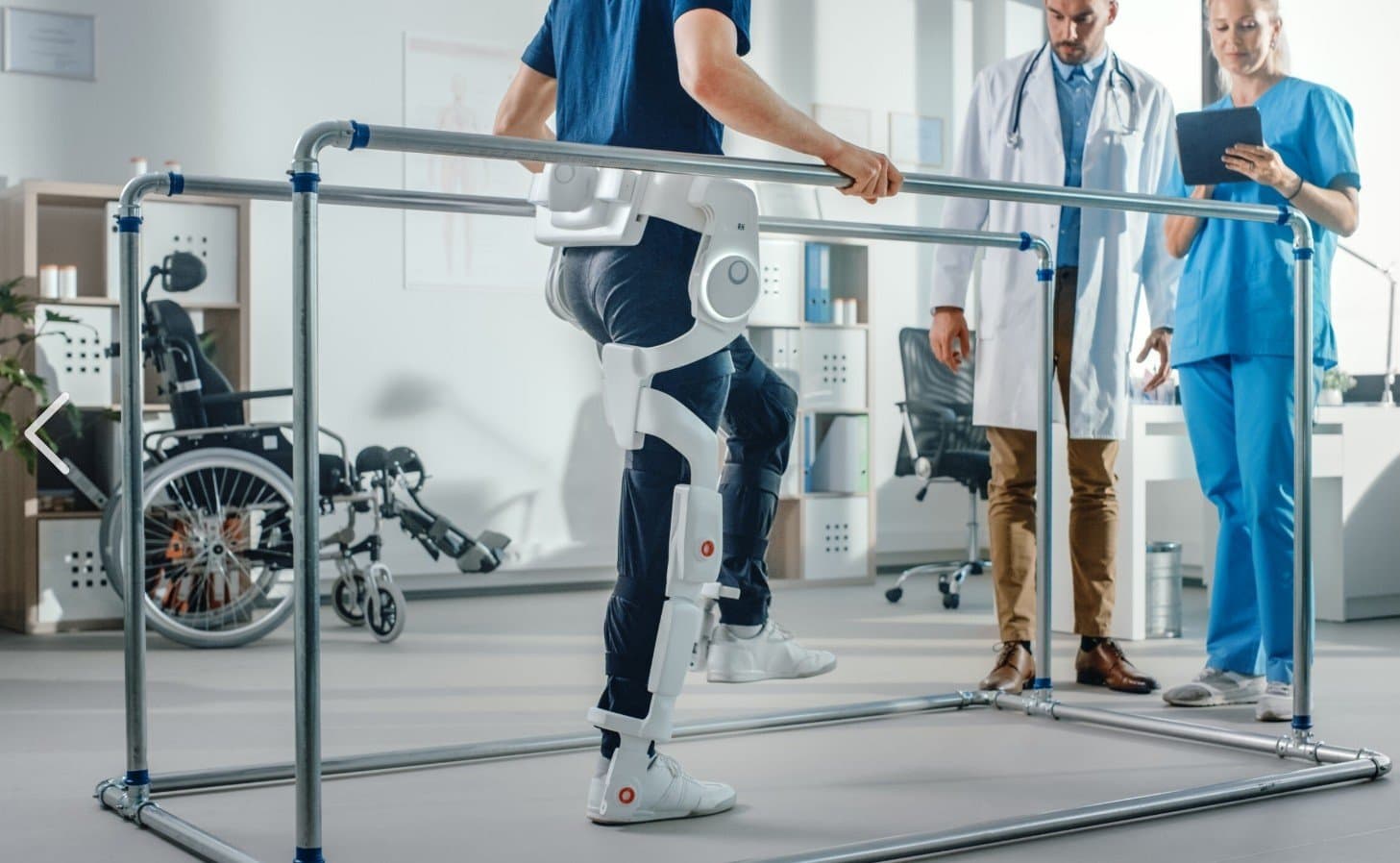 Patient walking with a robotic exoskeleton while clinicians observe